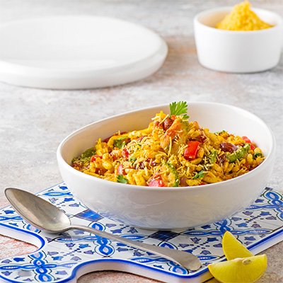 A vibrant serving of Bhelpuri, featuring puffed rice mixed with diced tomatoes, onions, and boiled potatoes, topped with tangy tamarind chutney, coriander, and crispy sev.